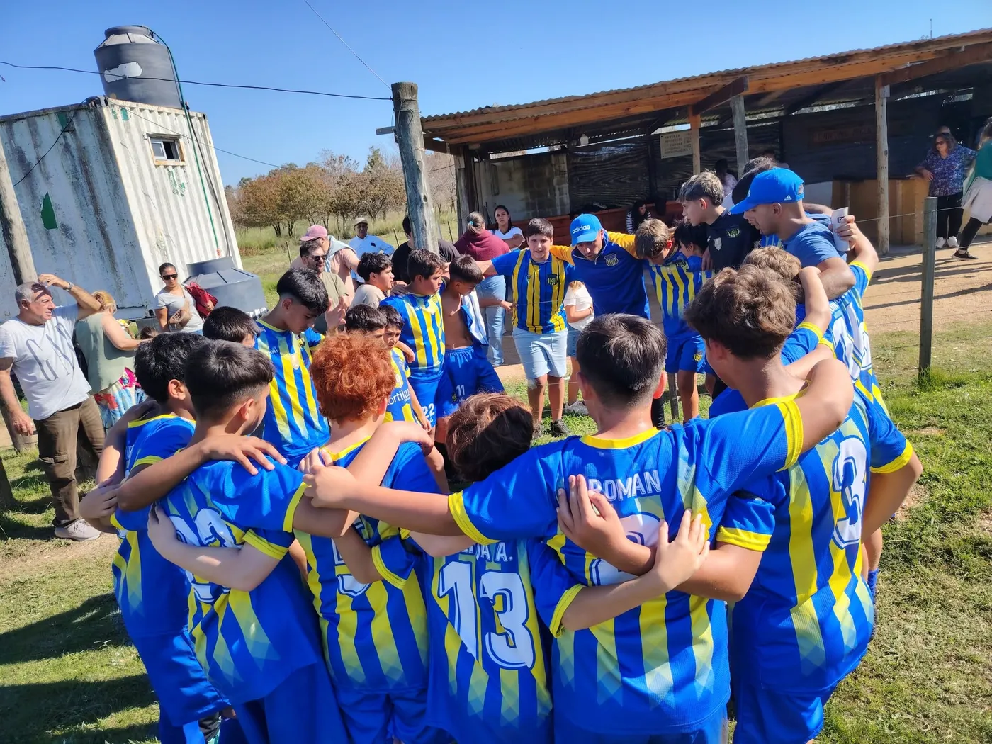 Los gurises de Juveniles del Campito en ronda antes de un partido, con las camisetas azules y amarillas